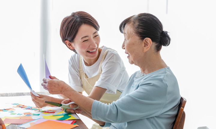 折り紙を折る職員と入居者